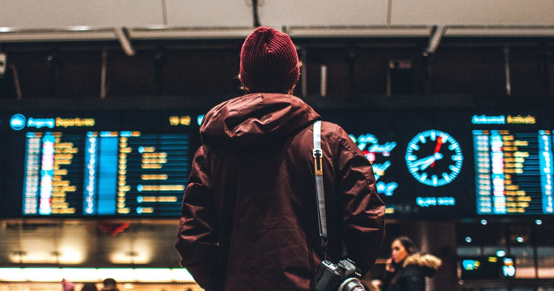 Traveller from behind reading an airport departure board — the moment many eSIM mistakes happen at the airport instead of being avoided beforehand.
