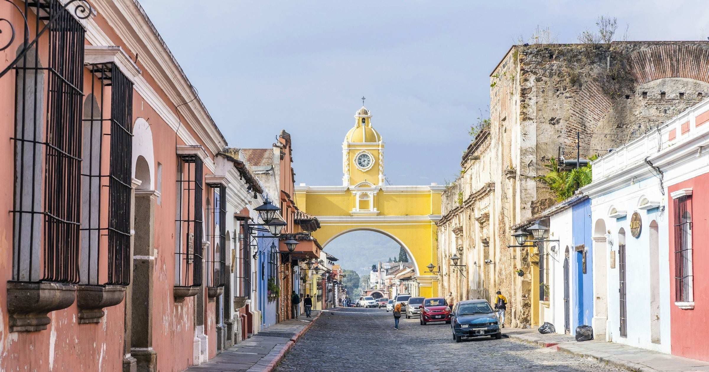 Cobblestone street in colonial Antigua, Guatemala framed by the iconic yellow Santa Catalina Arch.