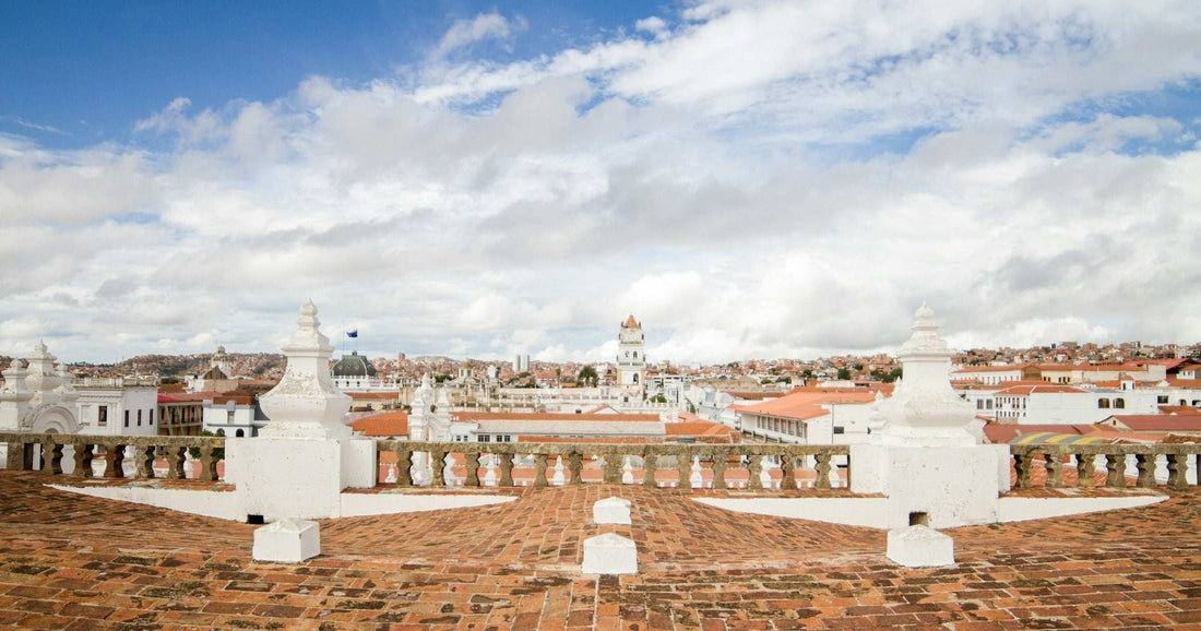 Sucre rooftop panorama with colonial white architecture and terracotta tiles under a bright blue sky — a popular South American destination for February travel.