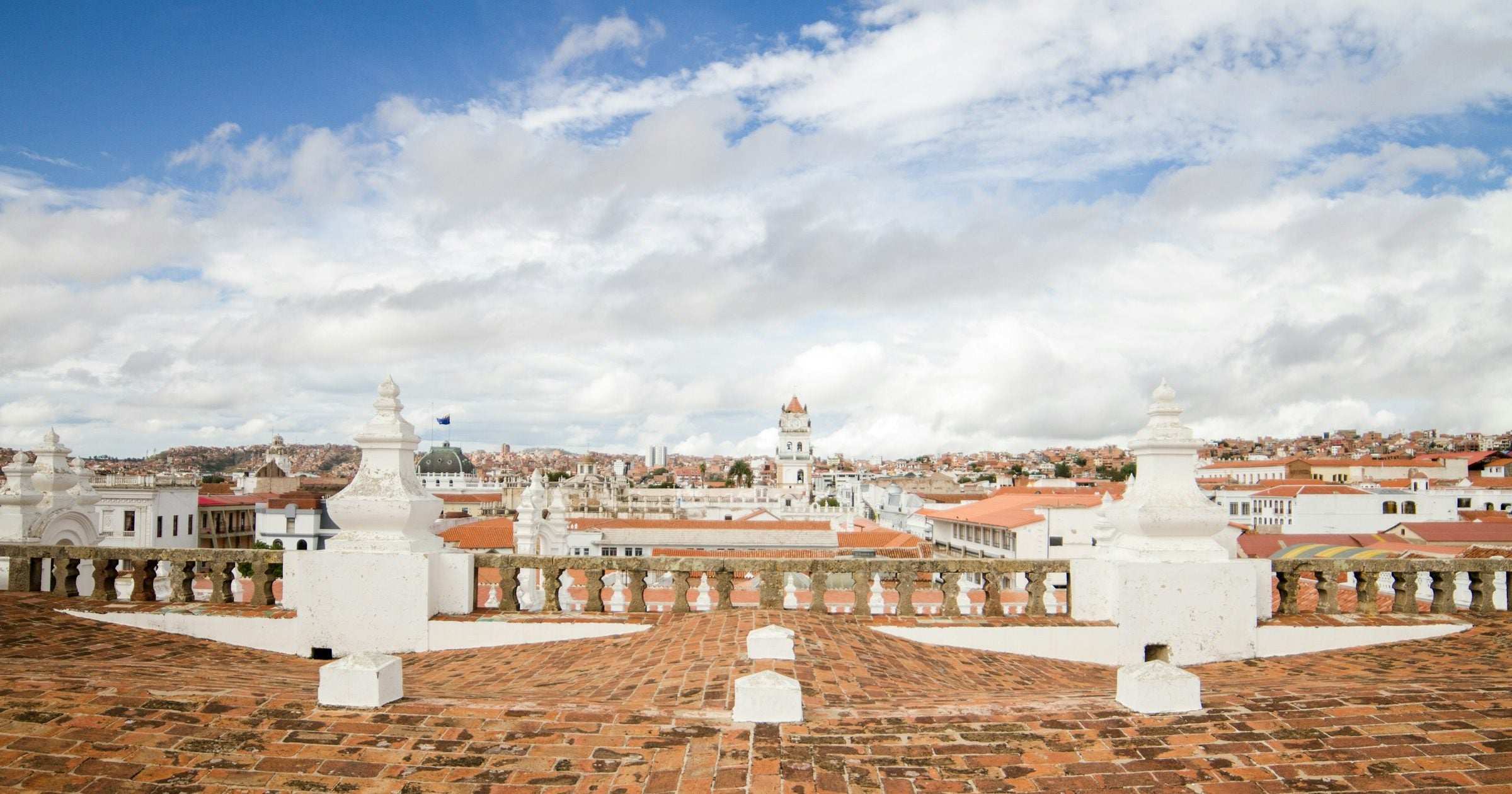 Sucre rooftop panorama with colonial white architecture and terracotta tiles under a bright blue sky — a popular South American destination for February travel.