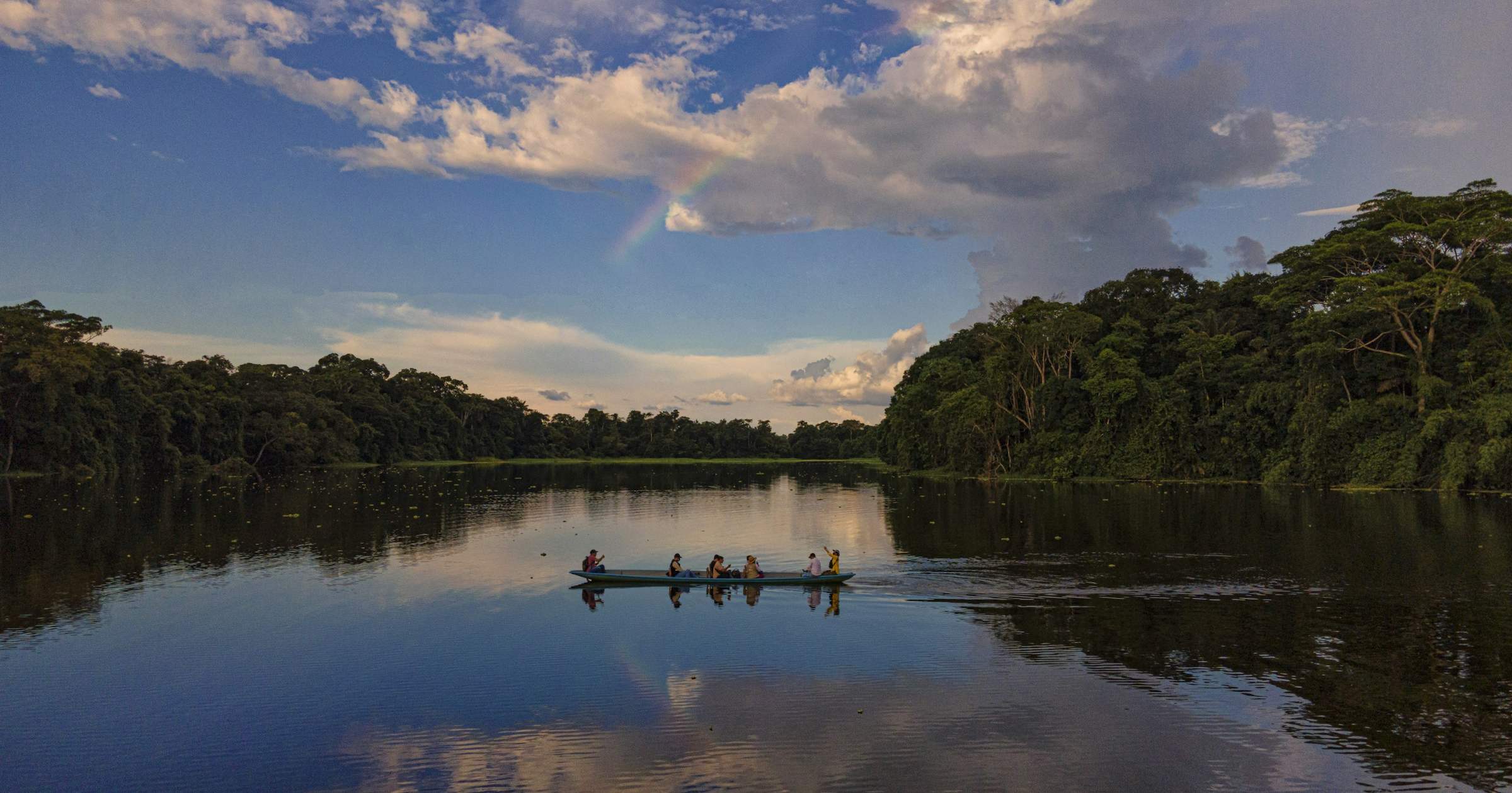 Travellers on a canoe exploring the Amazon River in Brazil surrounded by lush rainforest