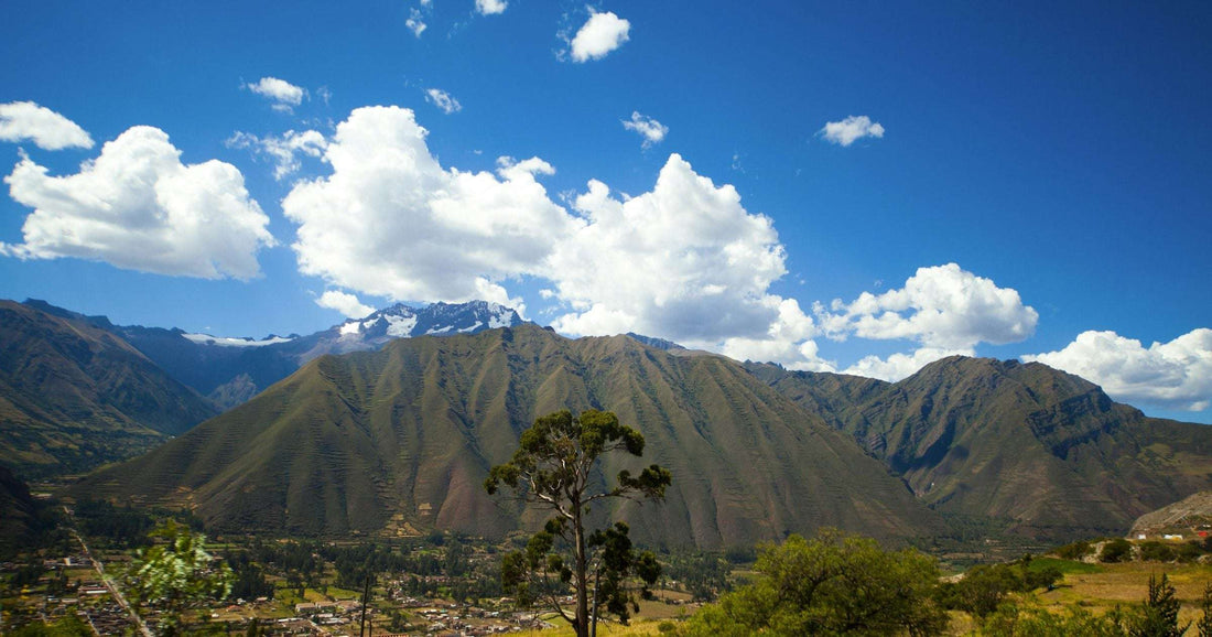Snow-capped Andean peak above the Sacred Valley with a small village below — Peru and other Andean countries are among the cheapest Latin American daily-budget destinations in 2026.
