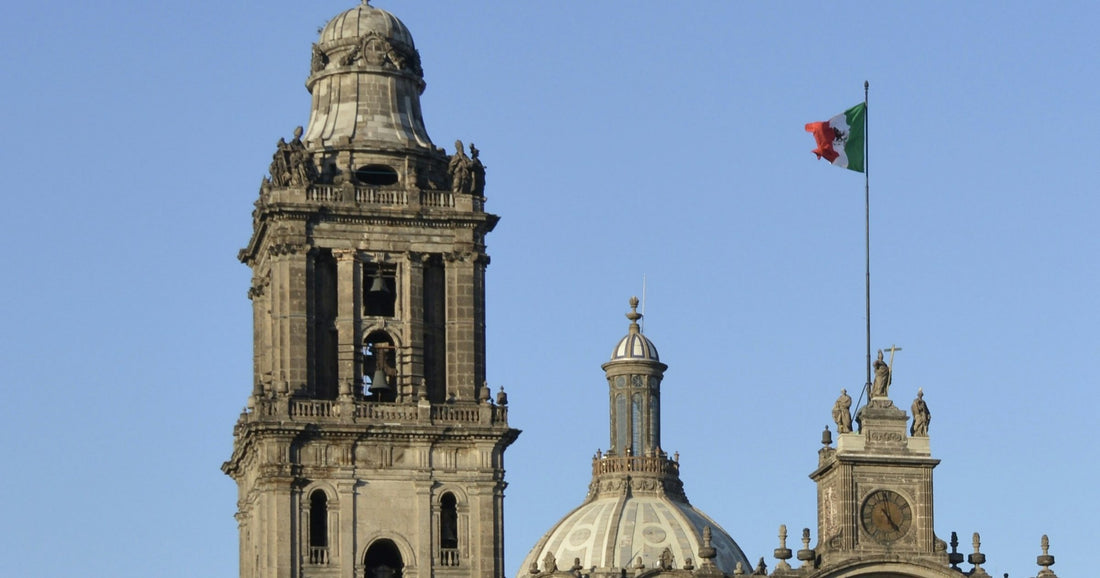 Catedral Metropolitana of Mexico City on the Zócalo with the Mexican flag against a clear blue sky — an iconic Mexico City landmark for travellers staying connected with an eSIM.