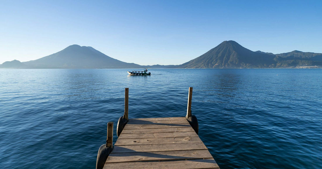 Wooden dock on Lake Atitlan, Guatemala, with twin volcanoes across the water — a landmark Central America travel scene