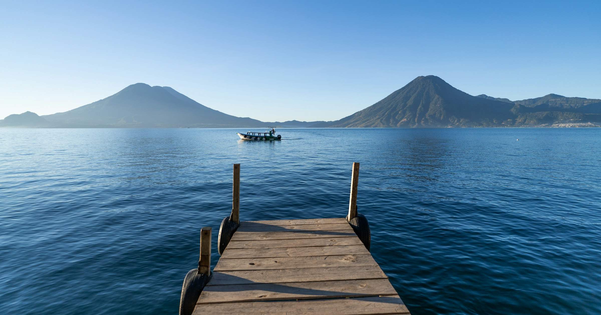 Wooden dock on Lake Atitlan, Guatemala, with twin volcanoes across the water — a landmark Central America travel scene