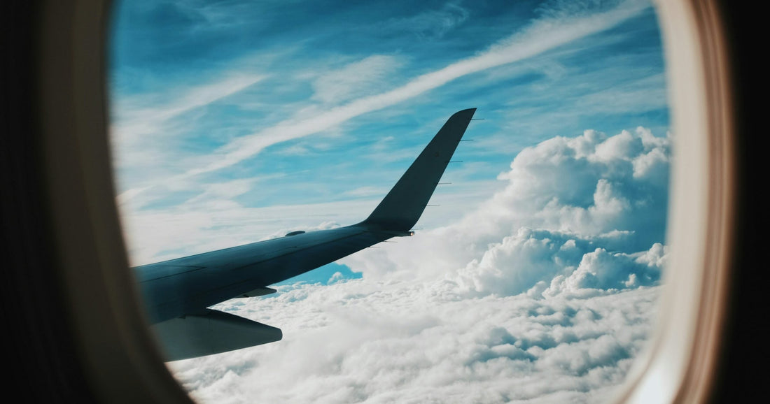 Airplane window view with wing above clouds — travelling to Canada