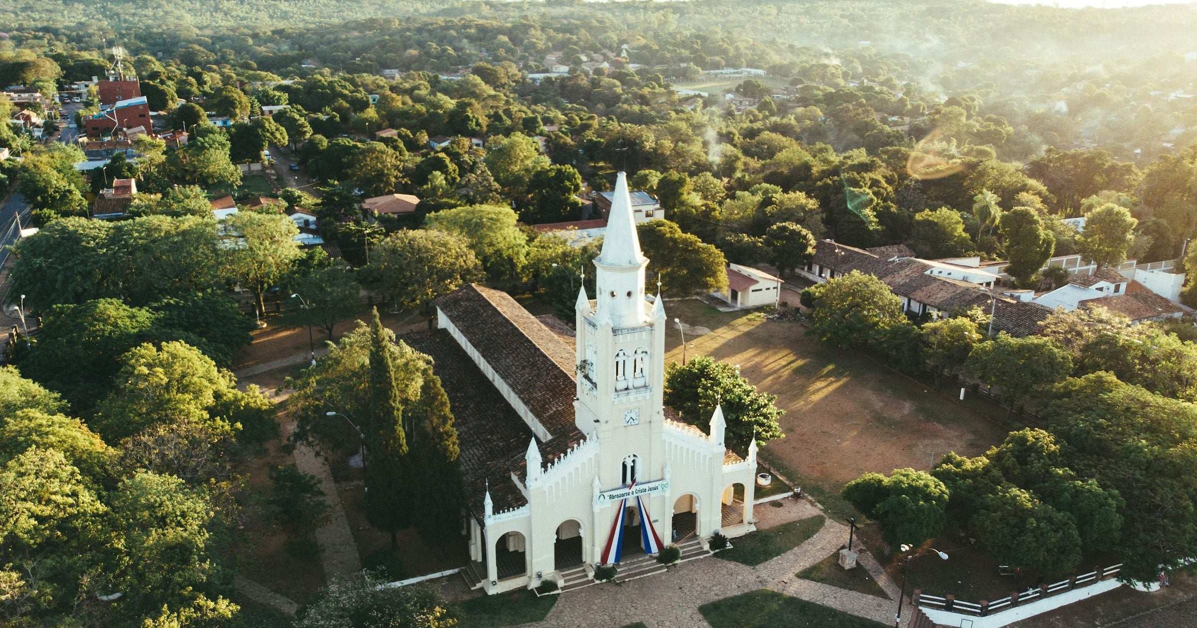 Aerial view of white colonial church in Paraguayan town surrounded by trees