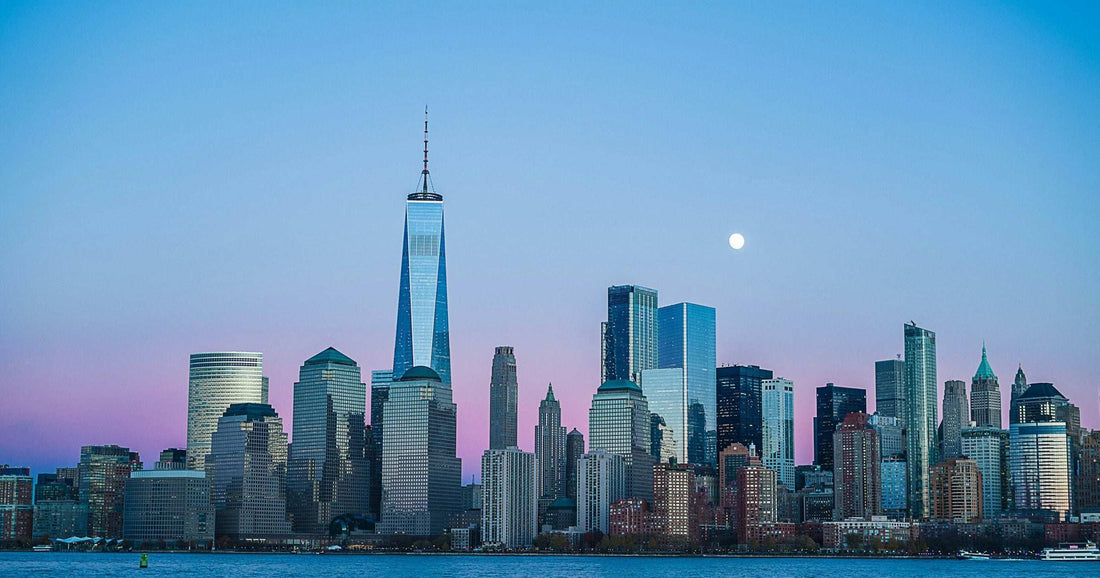 New York City skyline at twilight with One World Trade Center and the moon over the Hudson — visitor destination in the United States