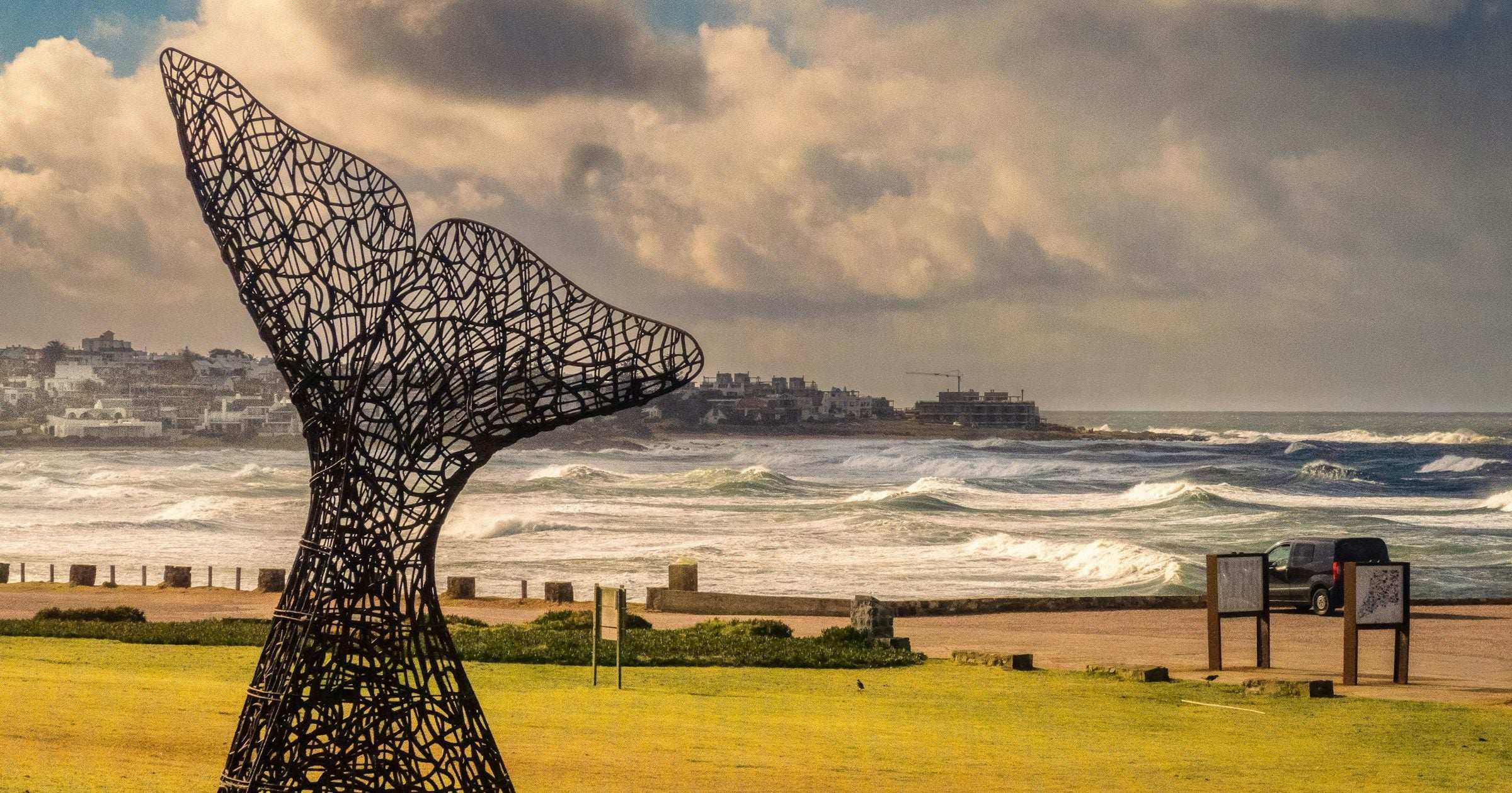 Whale tail sculpture on the Atlantic coast at Punta del Este, Uruguay with dramatic clouds and surf