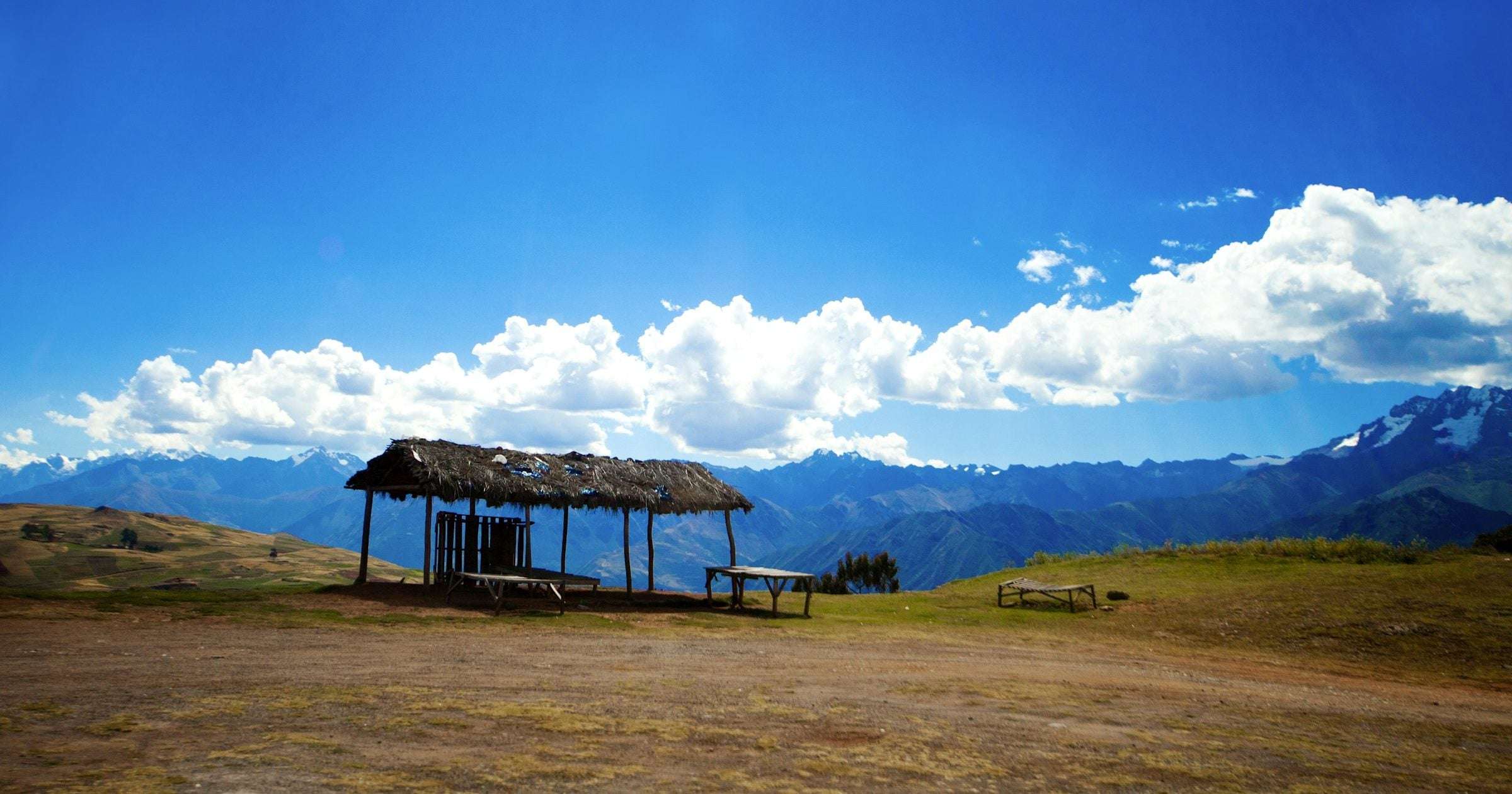 Open Andean plateau with a thatched shelter and snow-capped mountains across Latin America