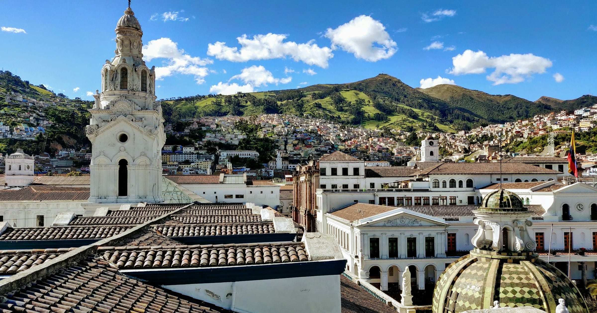 Quito old-town rooftops, church bell tower and Andean foothills in Ecuador — comparing eSIM vs physical SIM for South America travel.