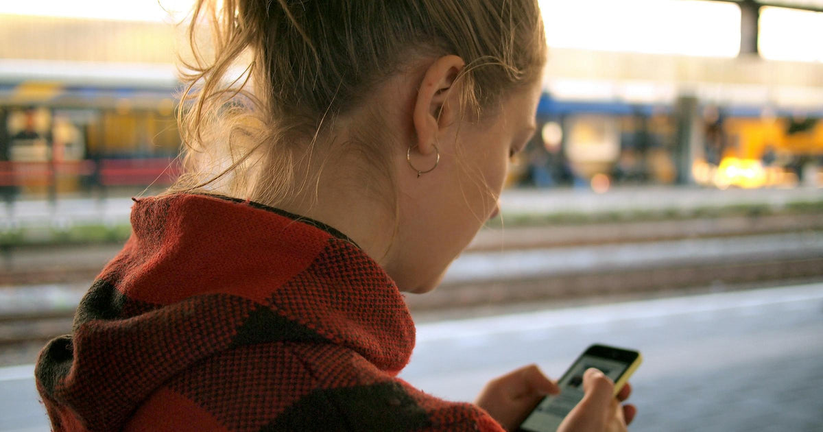 Traveller checking phone data and hotspot settings at a train station