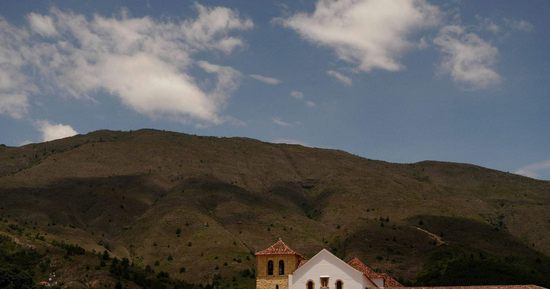 Colonial whitewashed town with bell tower set against rolling Andean hills in Latin America