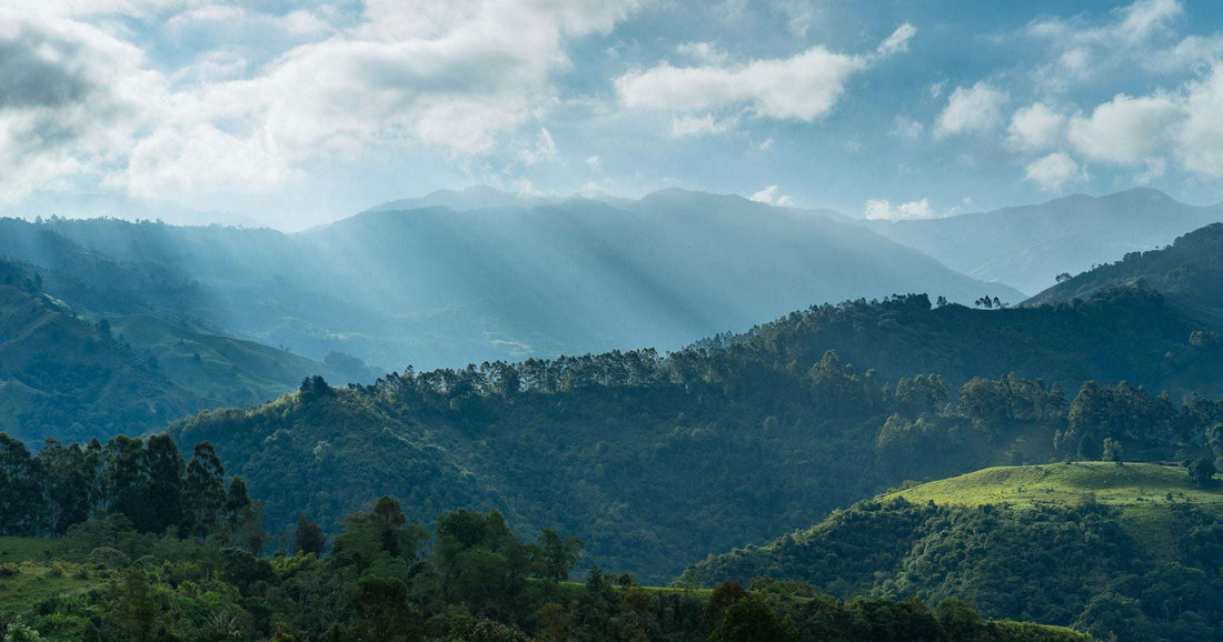 Sunrise rays over Andean ridges and forested hills in Colombia — a popular South American destination where travellers in 2026 plan multi-city trips through Bogotá, Medellín and Cartagena.
