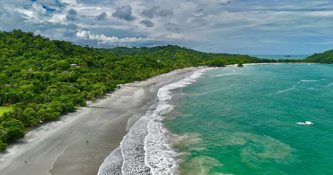 Aerial view of a Costa Rican Pacific coast beach lined with rainforest — Costa Rica ranks #1 in Central America's Global Peace Index in 2026.