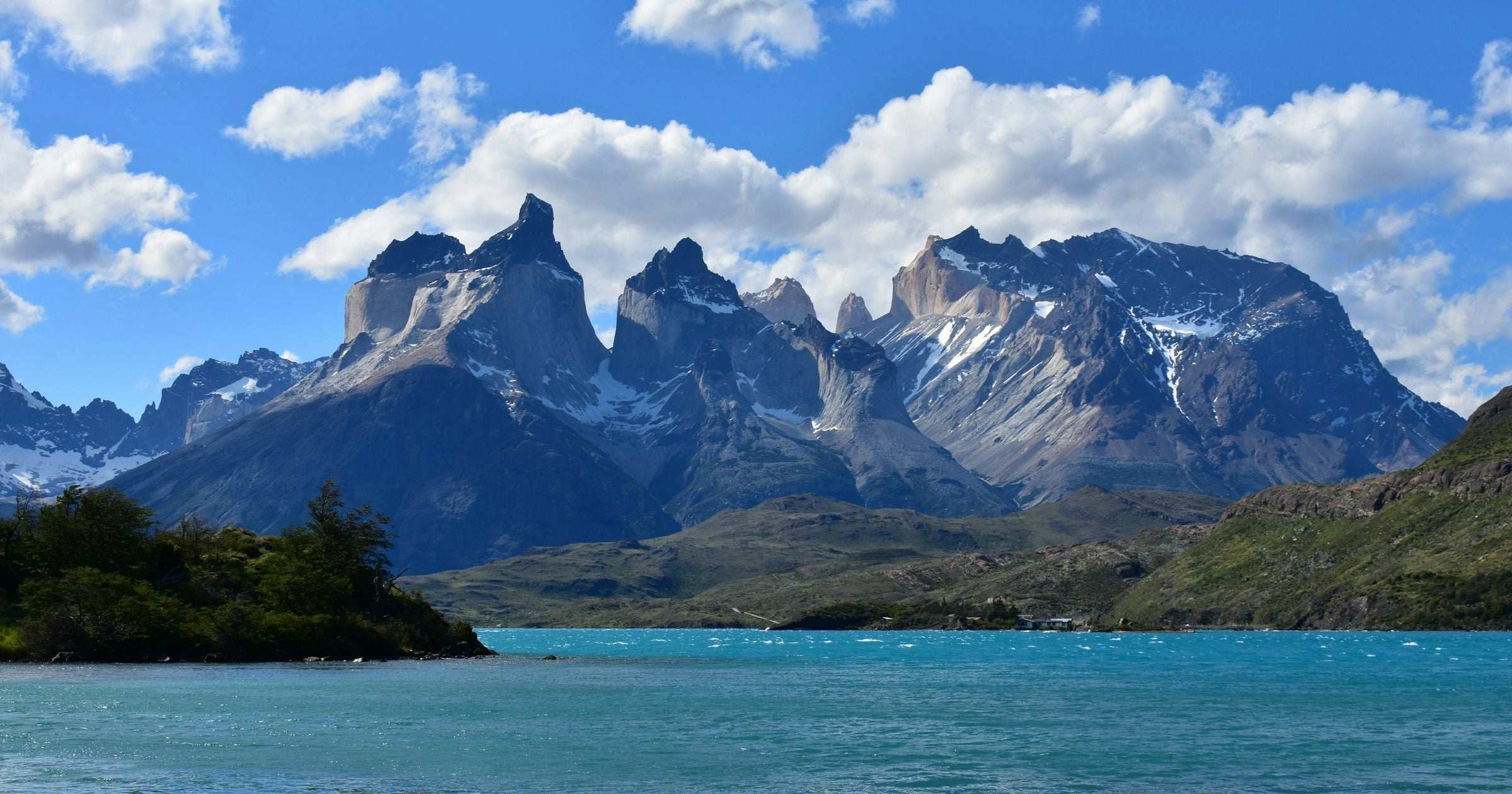 Torres del Paine Cuernos peaks rising above a turquoise lake under a bright blue summer sky — a family-friendly Patagonian destination in one of South America's safest-ranked countries.
