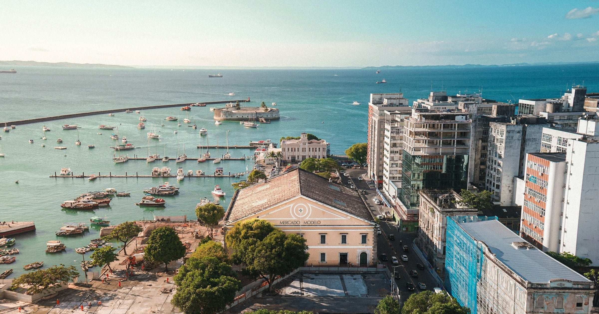 Aerial of Salvador da Bahia old town harbour with Mercado Modelo and palm-lined park — host city of Brazil's Salvador Carnival.