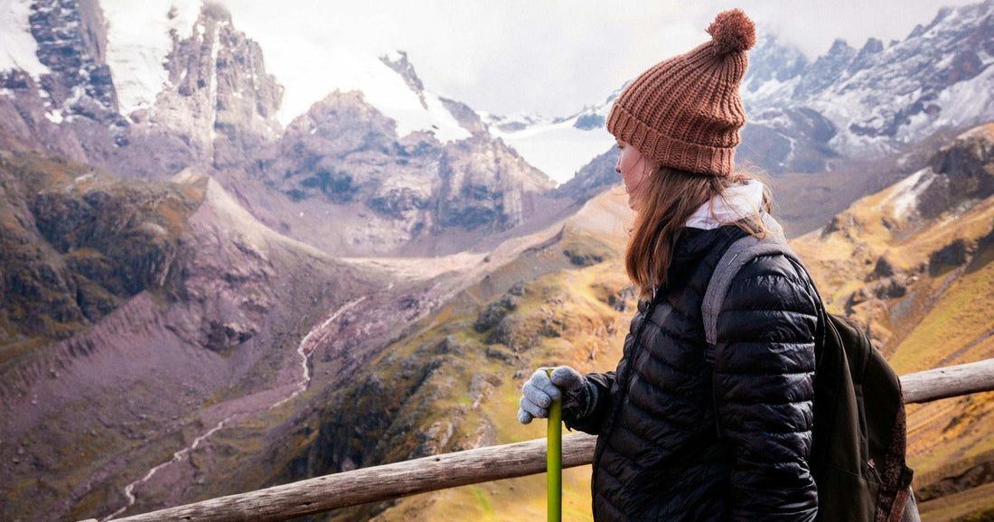 Solo female traveler in beanie and backpack overlooking the Peruvian Andes near Cusco — a popular safe base for women travelling alone in South America.