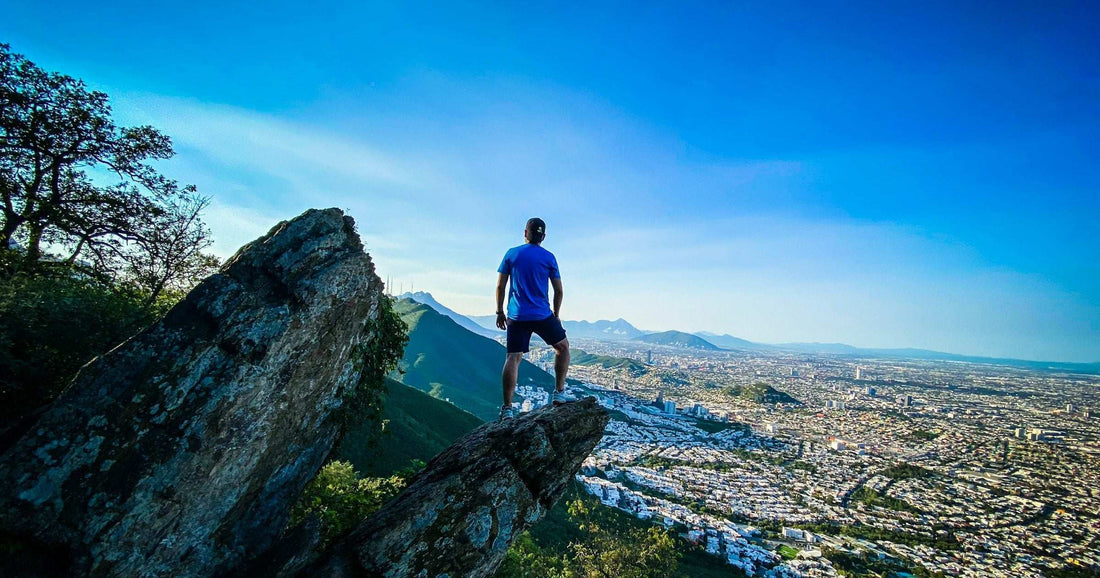Lone backpacker standing on a rock overlook above a Latin American city sprawl — a popular solo travel viewpoint for safety- and connectivity-conscious travellers.
