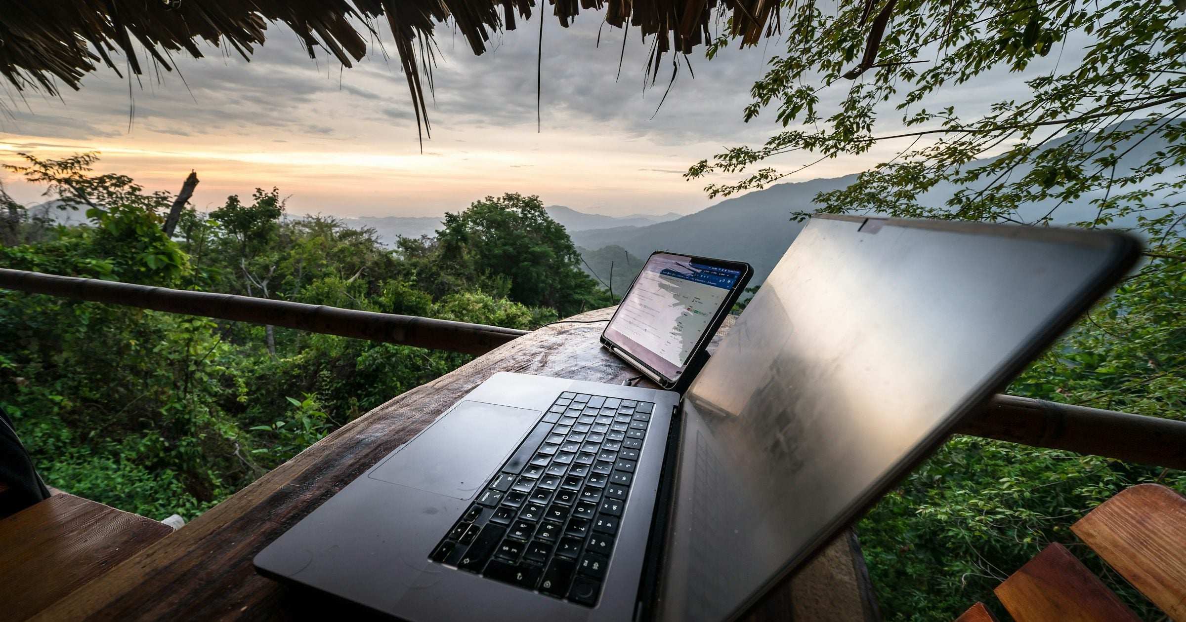 Laptop open on a wooden balcony with a view of mountains and jungle at golden hour in Latin America — a popular digital-nomad setting for travellers working remotely with an eSIM.